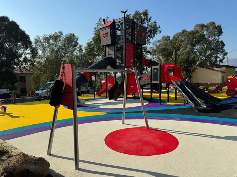 Salıncak takımı ve gri kırmızı oyun kulesiyle donatılmış renkli kauçuk zeminli oyun alanı