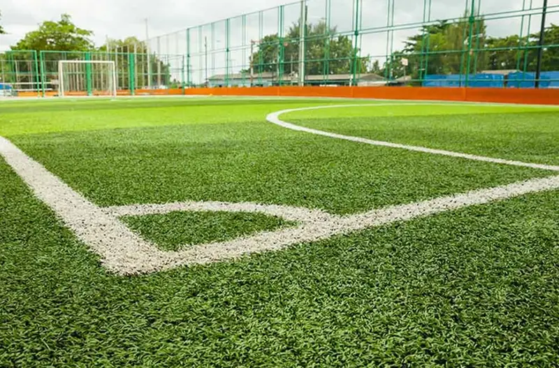 Suni çim futbol sahasında köşe çizgisi ve kum dolgulu yüzey