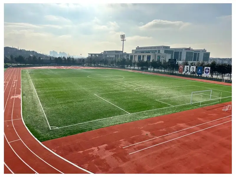 Tartan koşu pisti ile çevrelenmiş suni çim futbol sahası